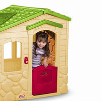 Load image into Gallery viewer, Child playing inside a colorful playhouse with a green roof and red door.