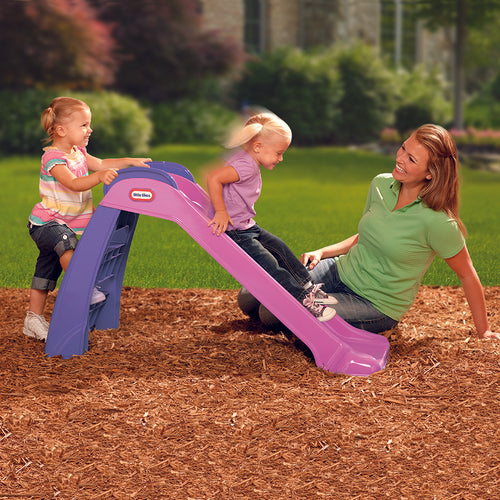 Two children playing on a purple slide with a woman nearby in a park setting.