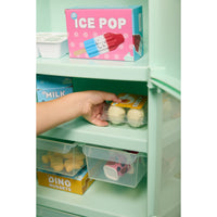 Load image into Gallery viewer, A hand placing a clear plastic drawer organizer into a mint green refrigerator shelf, with other toy food items and a pink 'ICE POP' box visible on the shelves.
