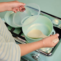 Load image into Gallery viewer, A person's hands are shown handling a mint green cooking pot and its matching lid on a retro-style mint green gas stove. A beige wooden spoon rests inside the pot.