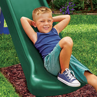 Load image into Gallery viewer, Child sitting on a green slide in a grassy area
