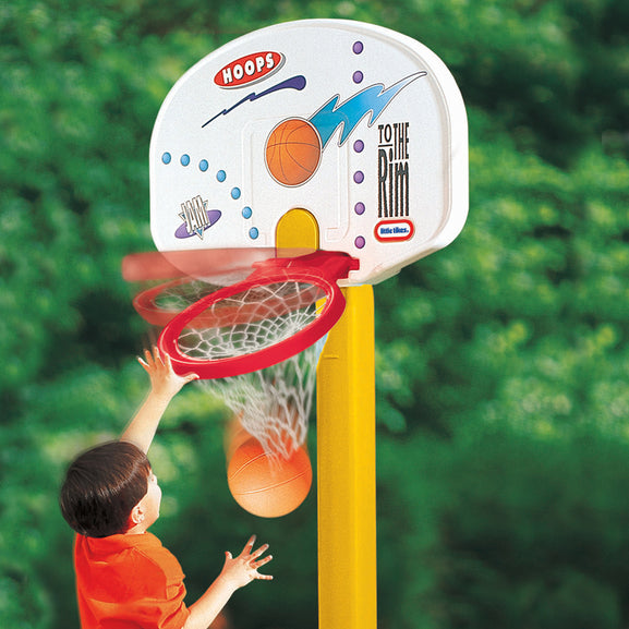 Child playing with a toy basketball hoop and ball outdoors.