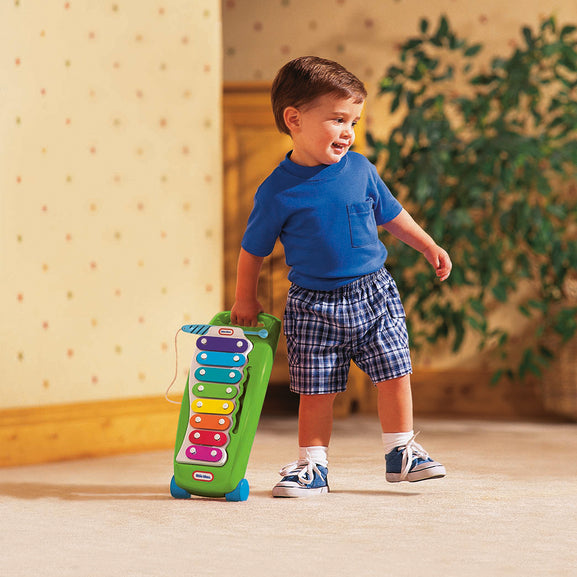 Child holding a colourful toy xylophone indoors