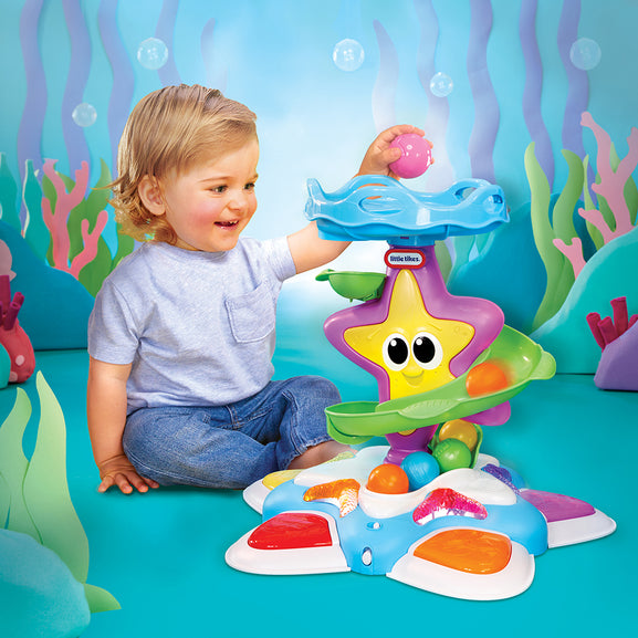 Child playing with a colourful toy in an underwater-themed setting