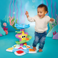 Load image into Gallery viewer, Child dancing with a colourful starfish toy in an underwater-themed setting
