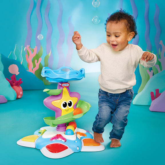 Child dancing with a colourful starfish toy in an underwater-themed setting