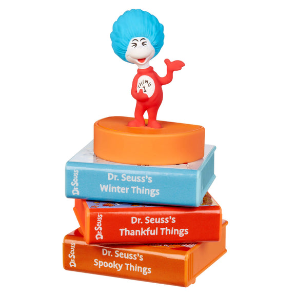 Thing one character from Dr. Seuss books on top of stacked books 