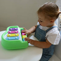 Load image into Gallery viewer, Child playing with a colorful toy keyboard on a white surface.
