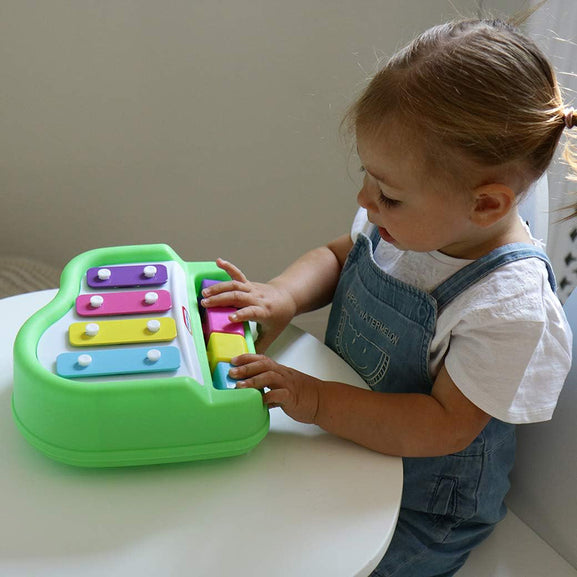 Child playing with a colorful toy keyboard on a white surface.