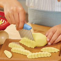 Load image into Gallery viewer, Child using a vegetable peeler to slice a sand potato 

