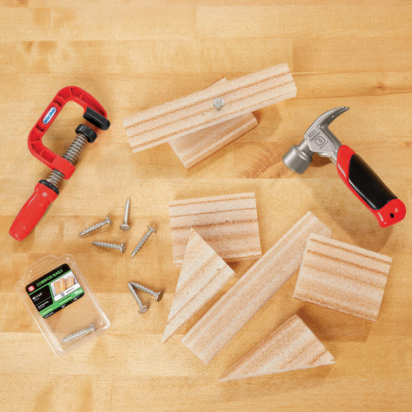 Woodworking tools and materials on a wooden surface including a clamp, hammer, wood pieces, and screws.