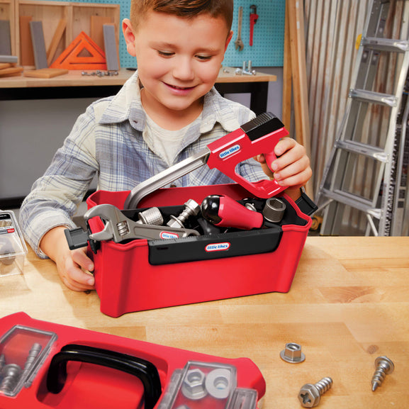 Child playing with a toy tool set on a wooden table
