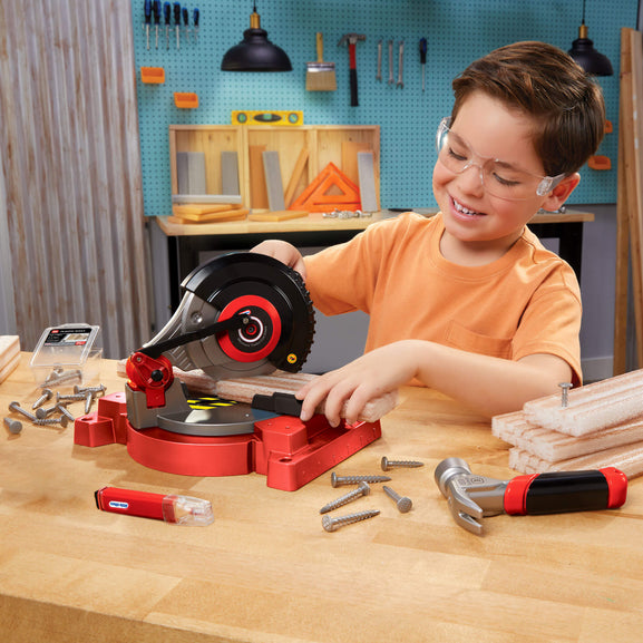 Child playing with toy power tool set in a workshop setting