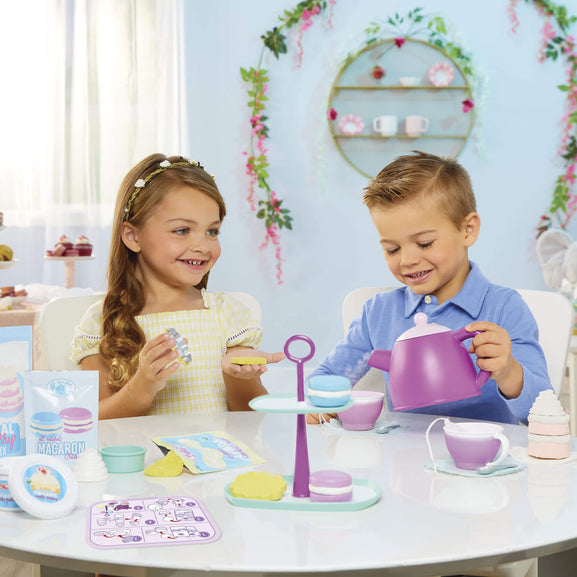 Two children playing with a toy tea set in a decorated room.