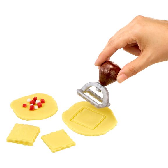 Hand using a ravioli pasta cutter on a white background