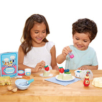 Load image into Gallery viewer, Two children playing with Pavlova and utensils on a wooden table.
