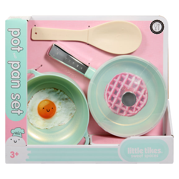 Little Tikes Sweet Spaces pot pan set in its original retail packaging, featuring a mint green frying pan with a waffle-shaped lid, a mint green frying pan with a fried egg toy, and a beige spatula on a pink background.