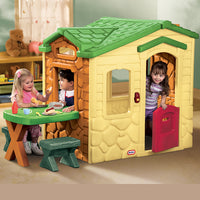 Load image into Gallery viewer, Children playing around a plastic playhouse with a green roof and yellow body.
