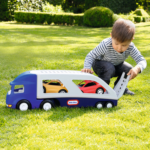 Child playing with a toy truck carrier on grass